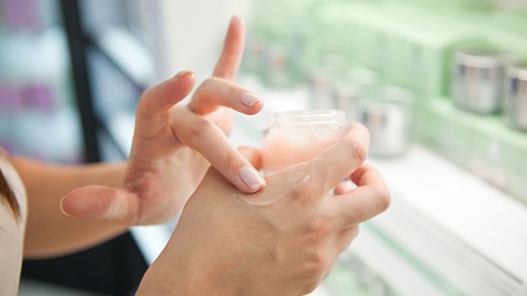 Mulher a colocar creme nas mãos